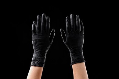 Photo of Man wearing latex gloves on black background, closeup