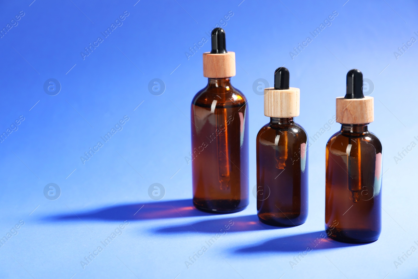 Photo of Bottles of skin care products on blue background, space for text