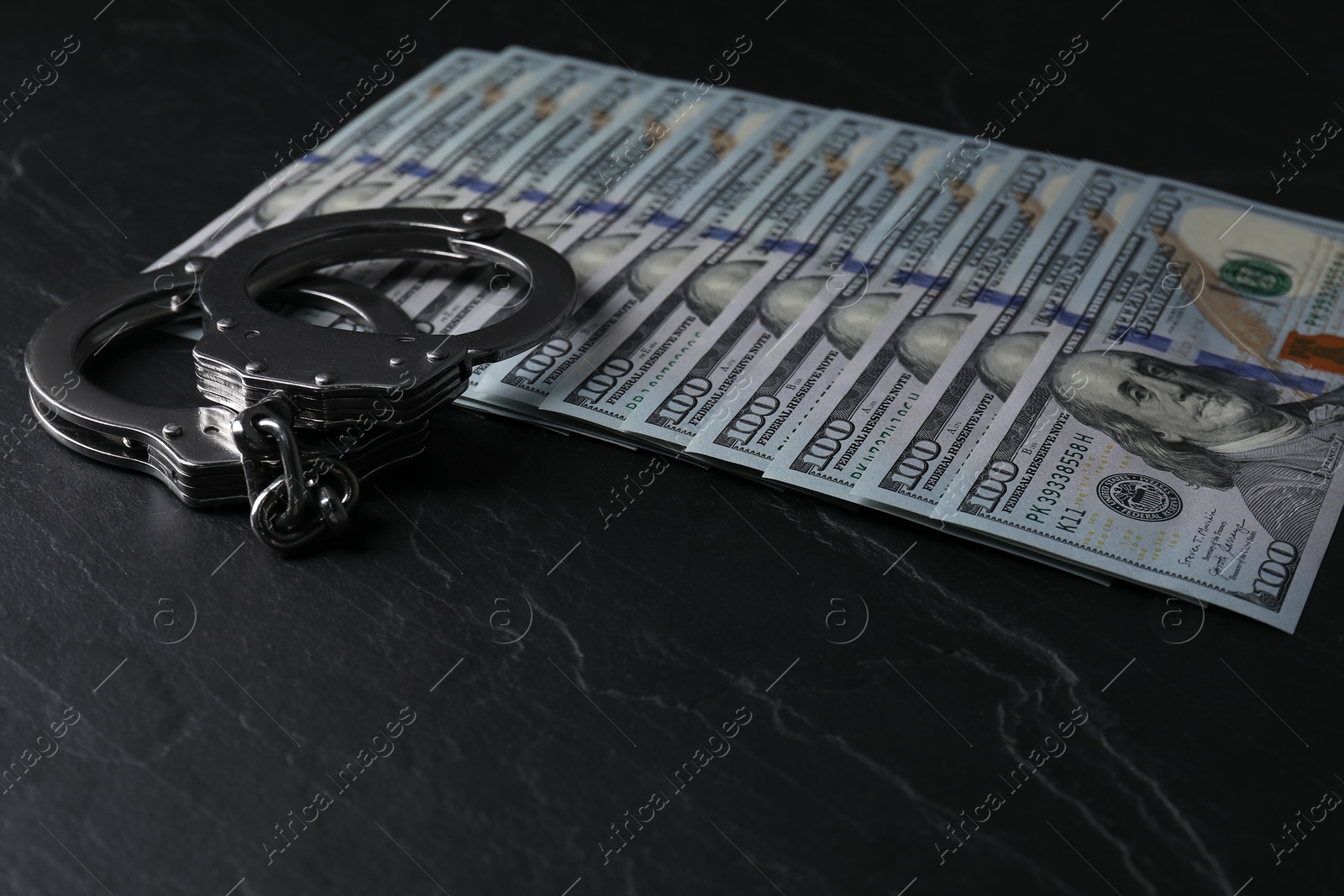 Photo of Corruption. Handcuffs and dollar banknotes on black table