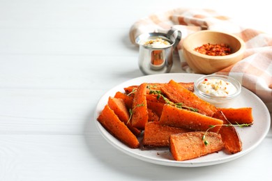 Photo of Pieces of tasty baked sweet potato with microgreens served on white wooden table, space for text