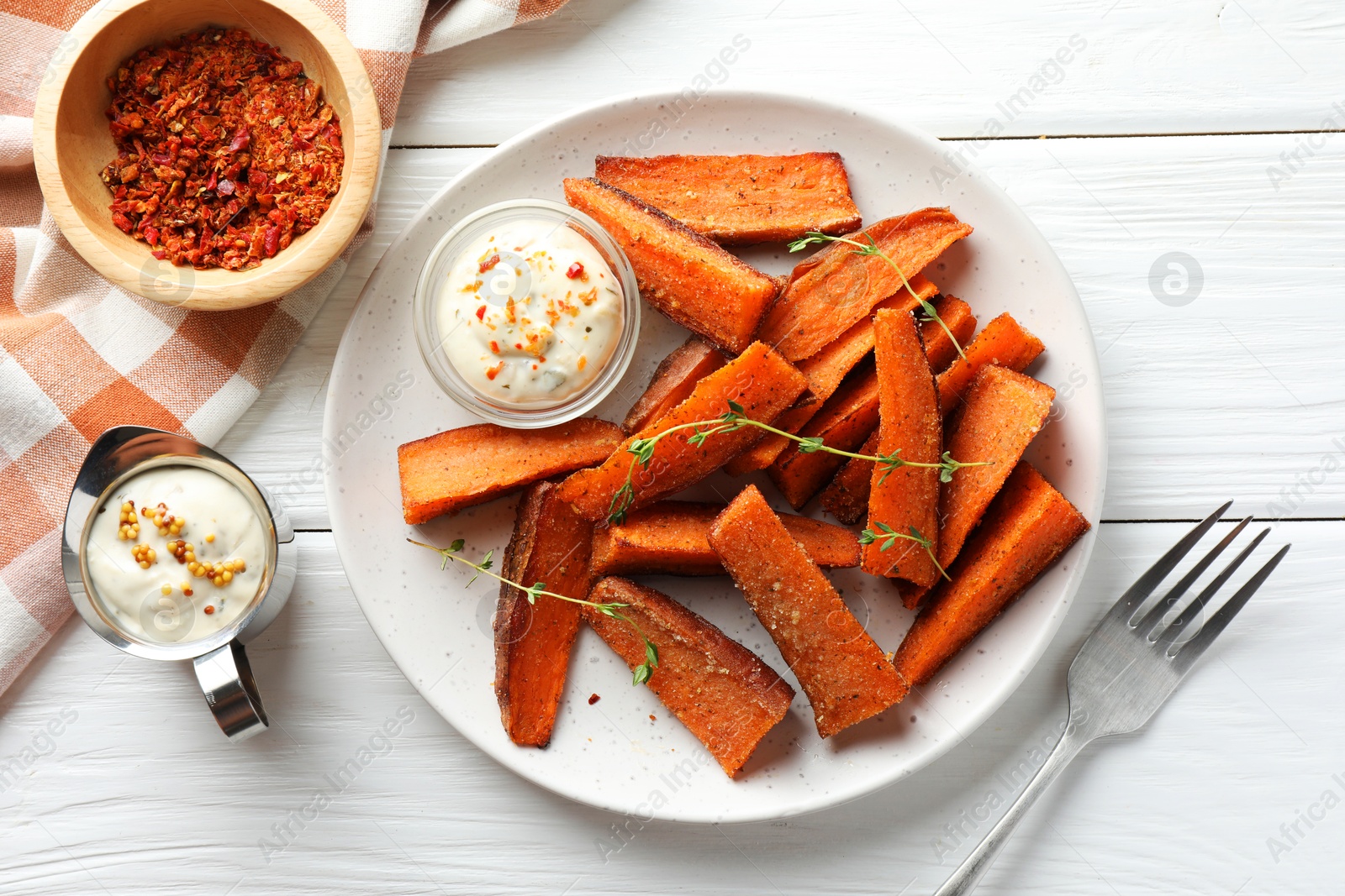 Photo of Pieces of tasty baked sweet potato with microgreens served on white wooden table, flat lay