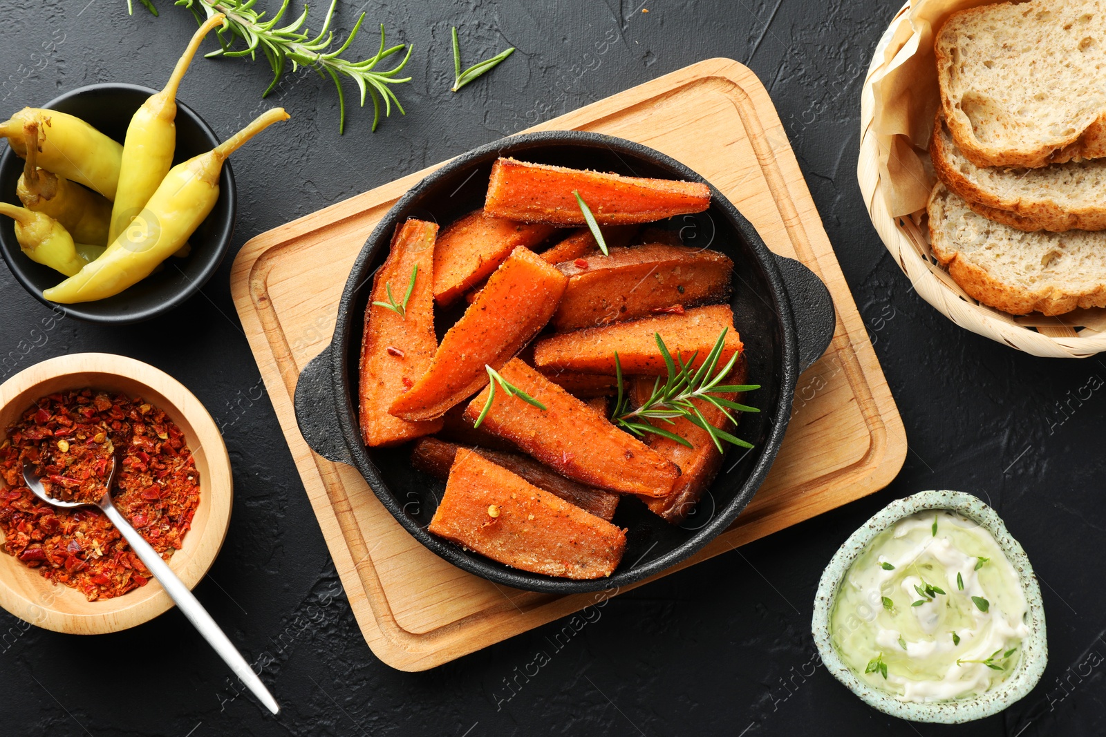 Photo of Tasty cooked sweet potato in baking dish served on grey textured table, flat lay