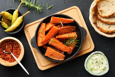 Photo of Tasty cooked sweet potato in baking dish served on grey textured table, flat lay