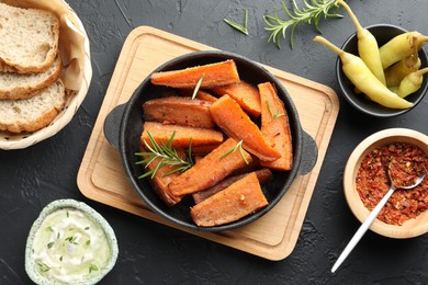 Photo of Tasty cooked sweet potato in baking dish served on grey textured table, flat lay