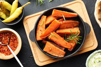 Photo of Tasty cooked sweet potato in baking dish served on grey textured table, flat lay