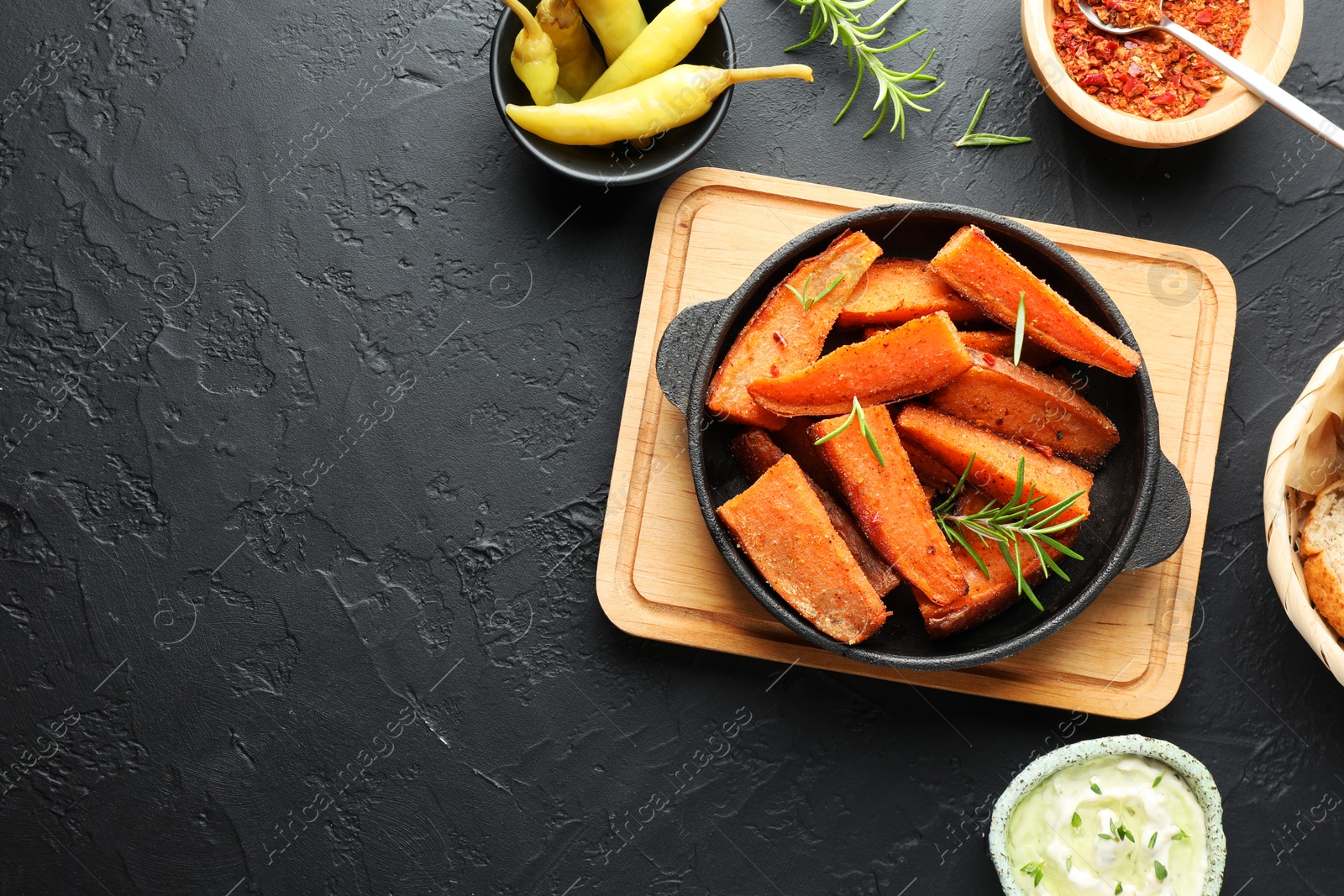 Photo of Tasty cooked sweet potato in baking dish served on grey textured table, flat lay. Space for text