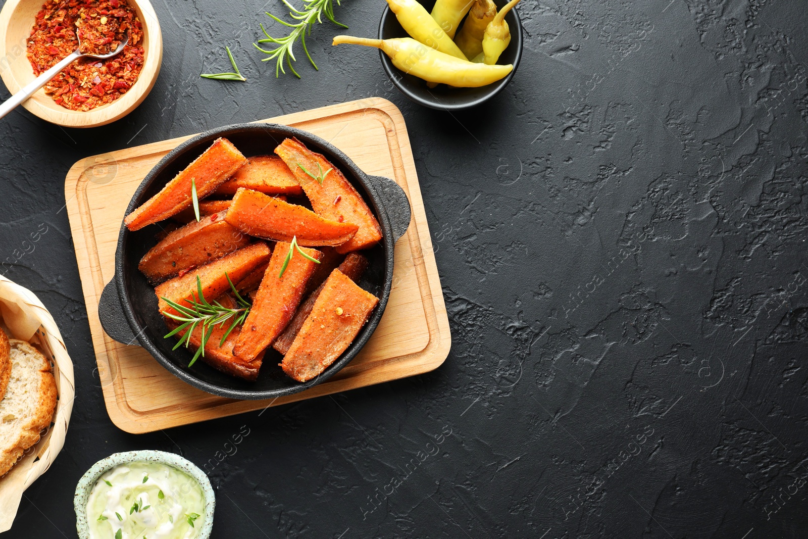 Photo of Tasty cooked sweet potato in baking dish served on grey textured table, flat lay. Space for text