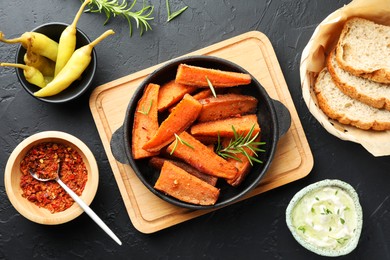 Photo of Tasty cooked sweet potato in baking dish served on grey textured table, flat lay