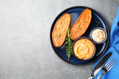 Photo of Halves of tasty baked sweet potato served on grey textured table, flat lay