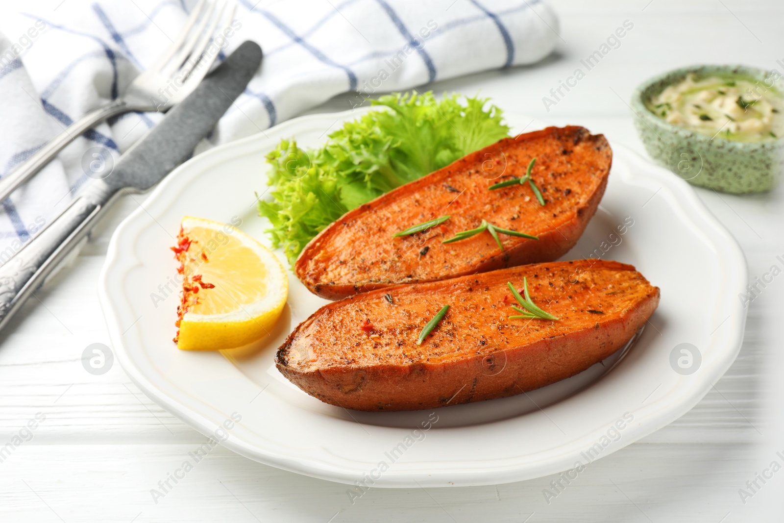 Photo of Tasty baked sweet potato served on white wooden table, closeup