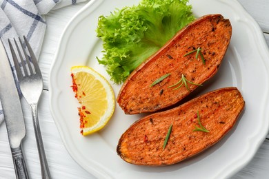 Photo of Tasty baked sweet potato served on white wooden table, flat lay