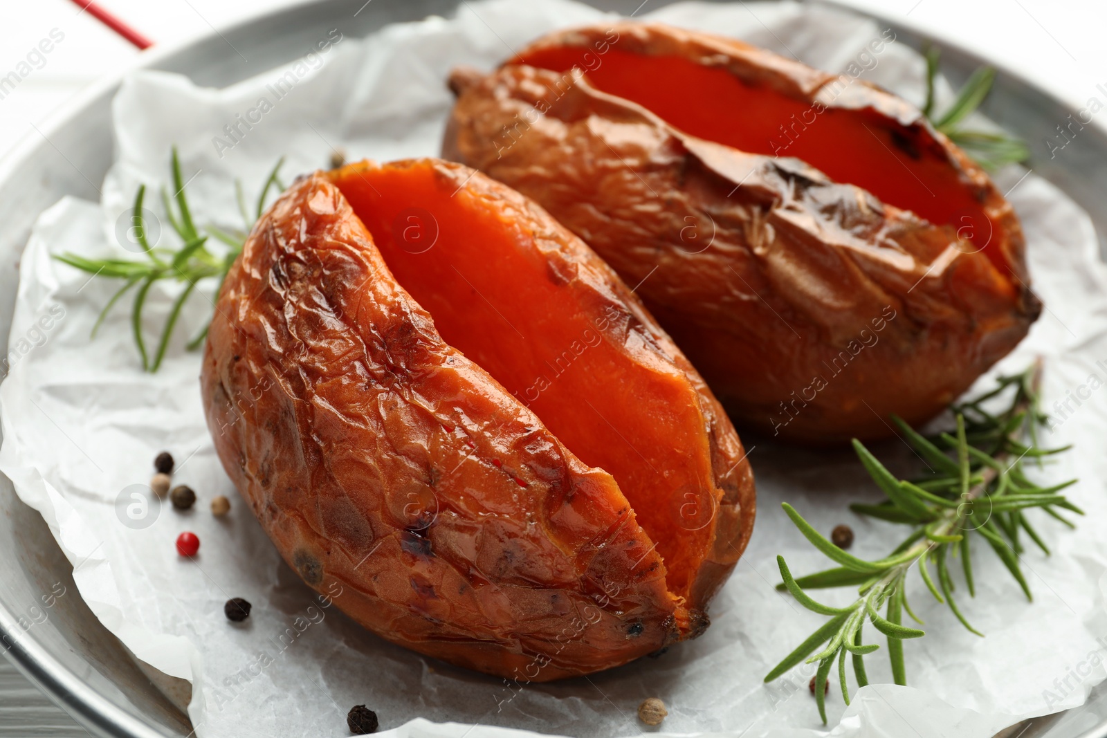 Photo of Tasty cooked sweet potatoes with rosemary on table, closeup