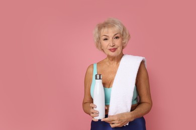 Photo of Senior woman with towel and water on pink background, space for text