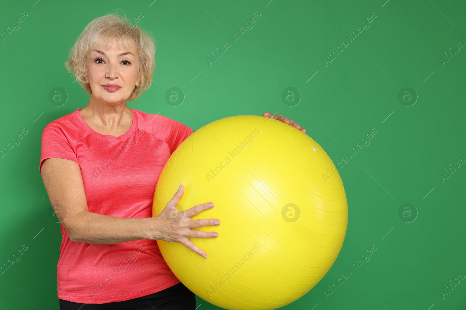 Photo of Senior woman with fitness ball on green background