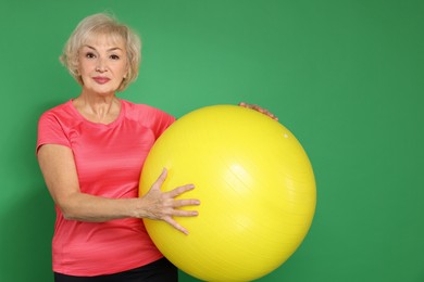 Photo of Senior woman with fitness ball on green background