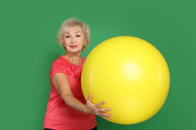 Photo of Senior woman with fitness ball on green background