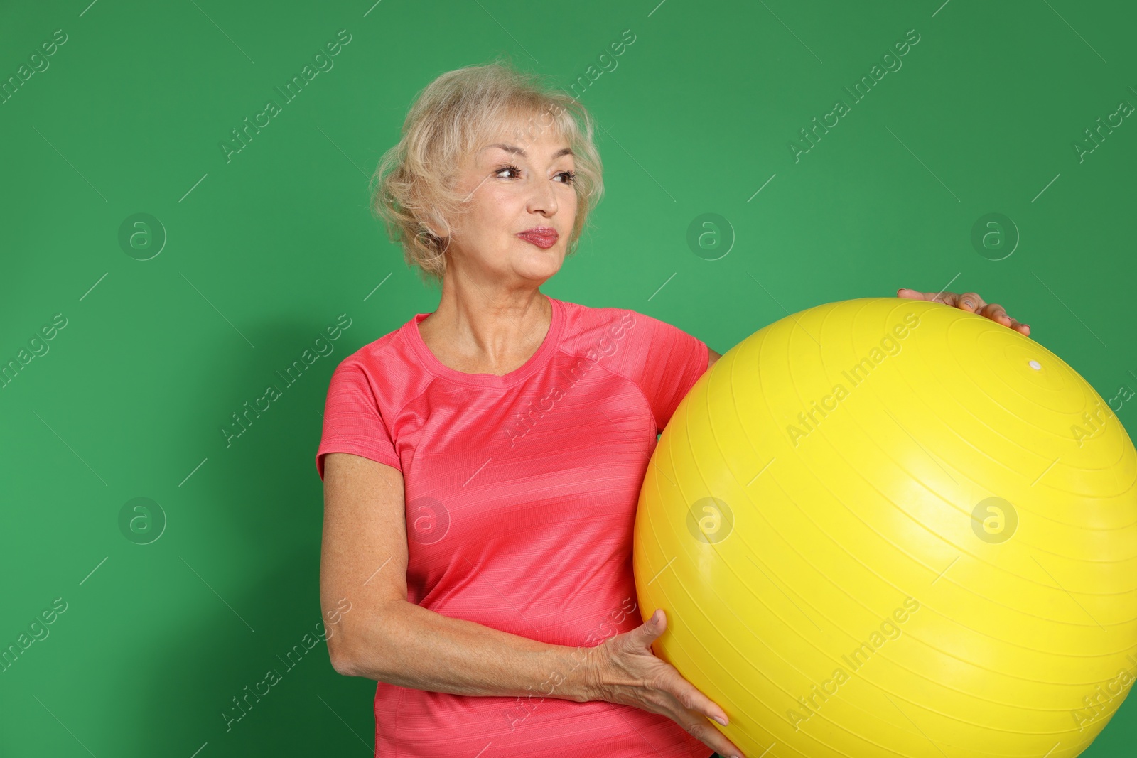 Photo of Senior woman with fitness ball on green background