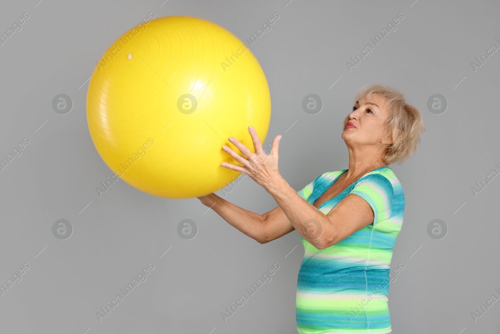 Photo of Senior woman with fitness ball on light grey background