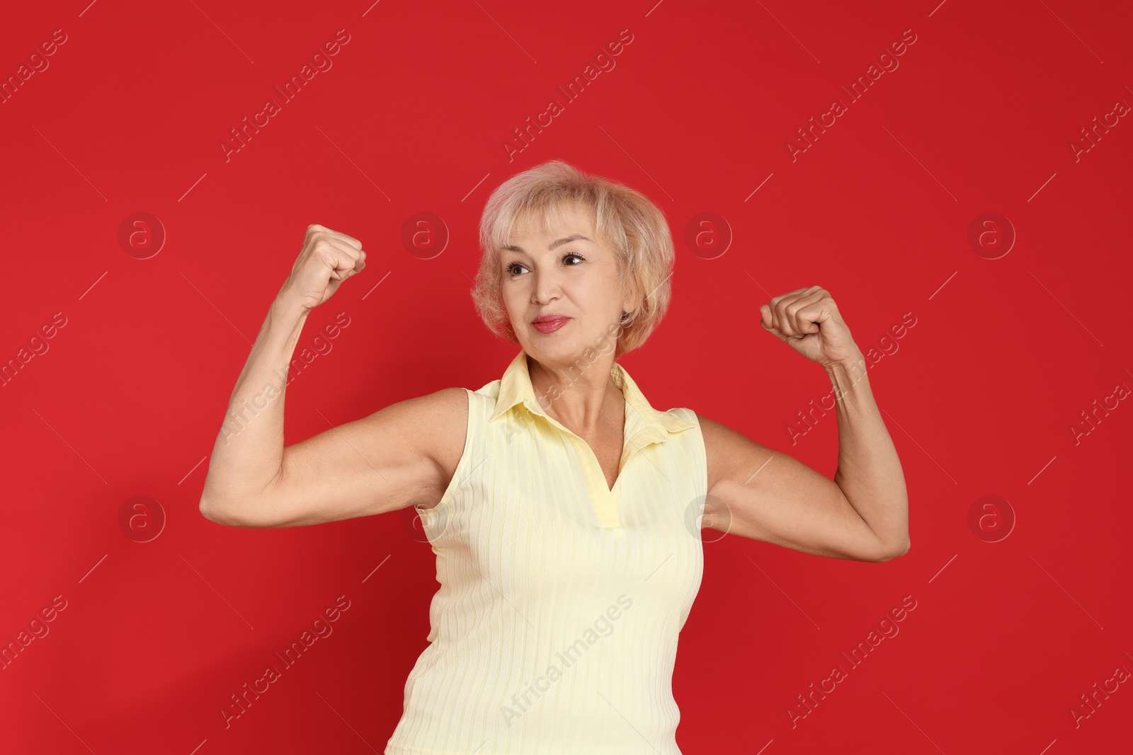 Photo of Senior woman exercising on red background. Healthy lifestyle