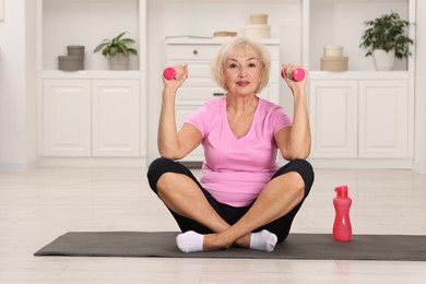 Photo of Senior woman exercising with fitness mat and dumbbells at home