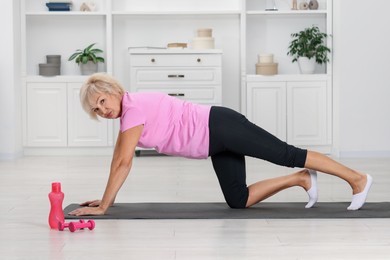 Photo of Senior woman exercising with fitness mat at home