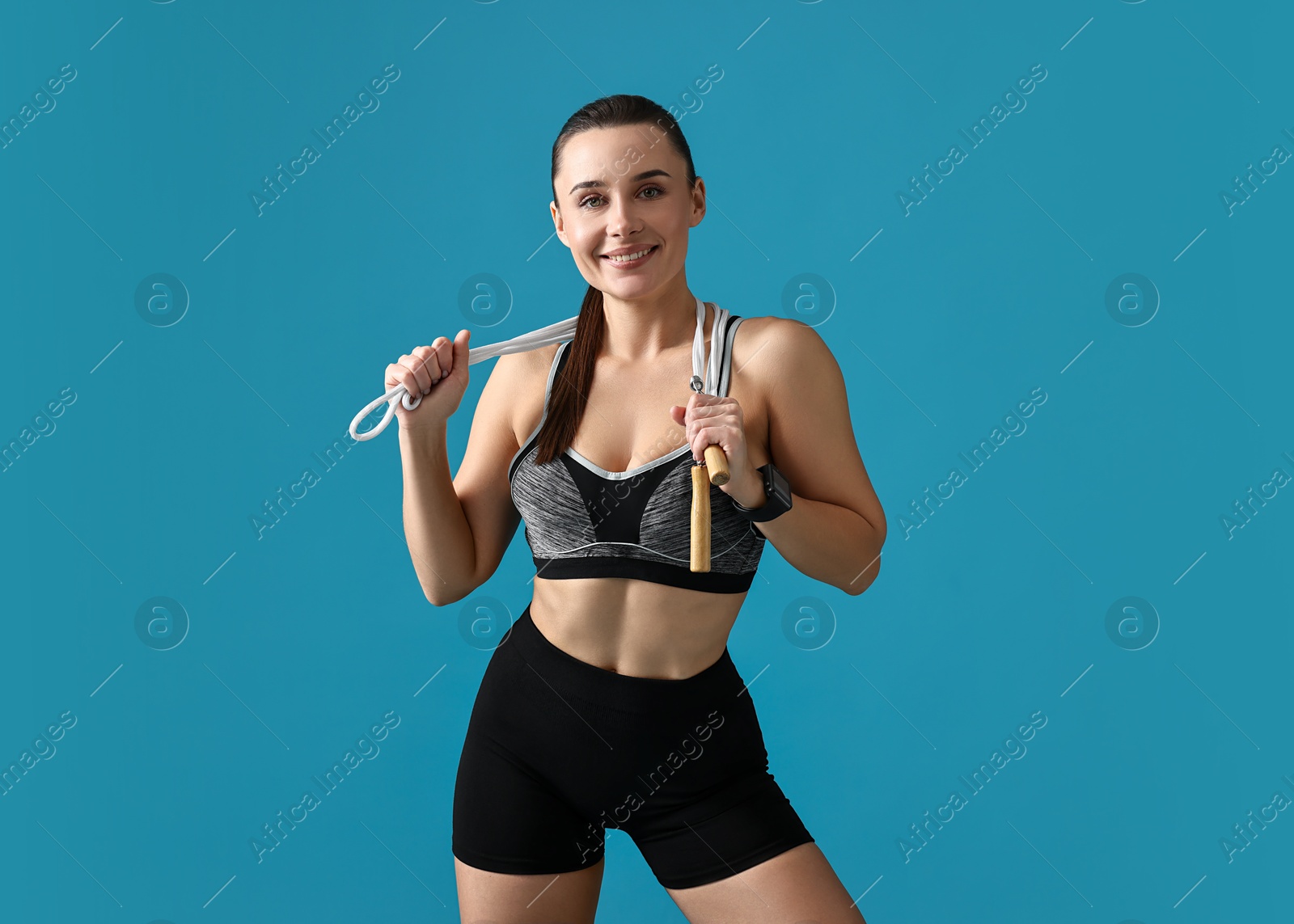 Photo of Woman in gym clothes with skipping rope on light blue background