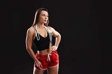 Photo of Woman in gym clothes with skipping rope on black background, space for text