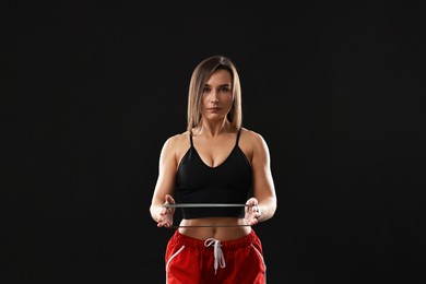 Photo of Woman in gym clothes with elastic band on black background