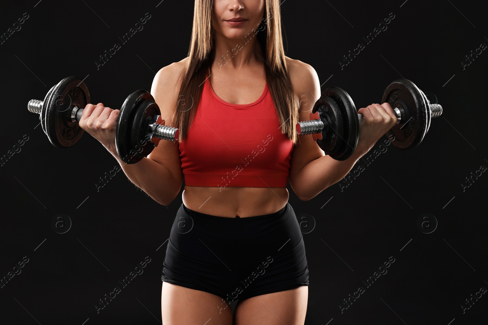 Photo of Woman in gym clothes exercising with barbells on black background, closeup