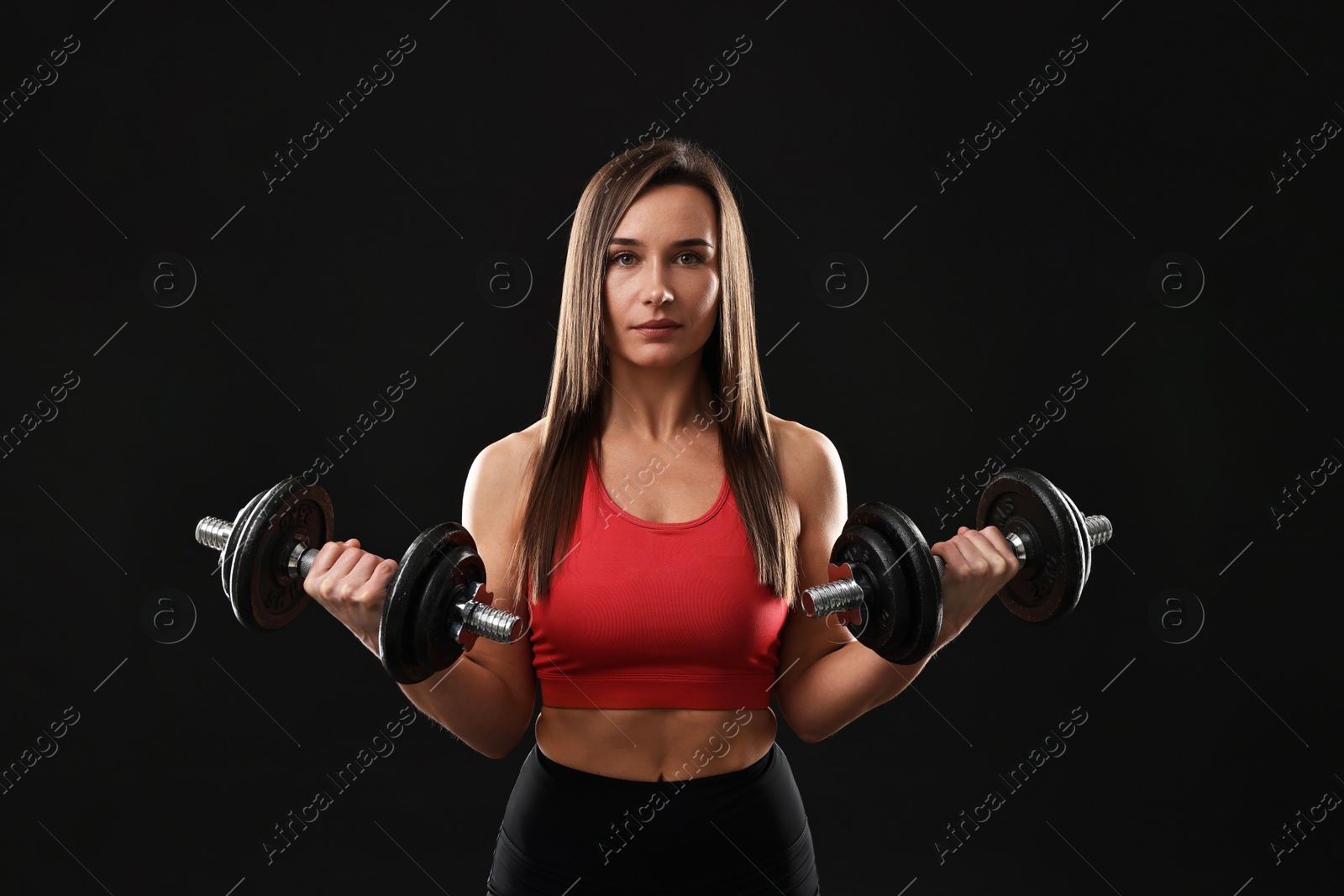 Photo of Woman in gym clothes exercising with barbell on black background