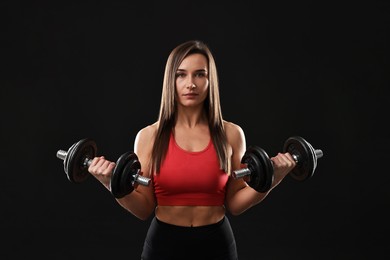 Photo of Woman in gym clothes exercising with barbell on black background