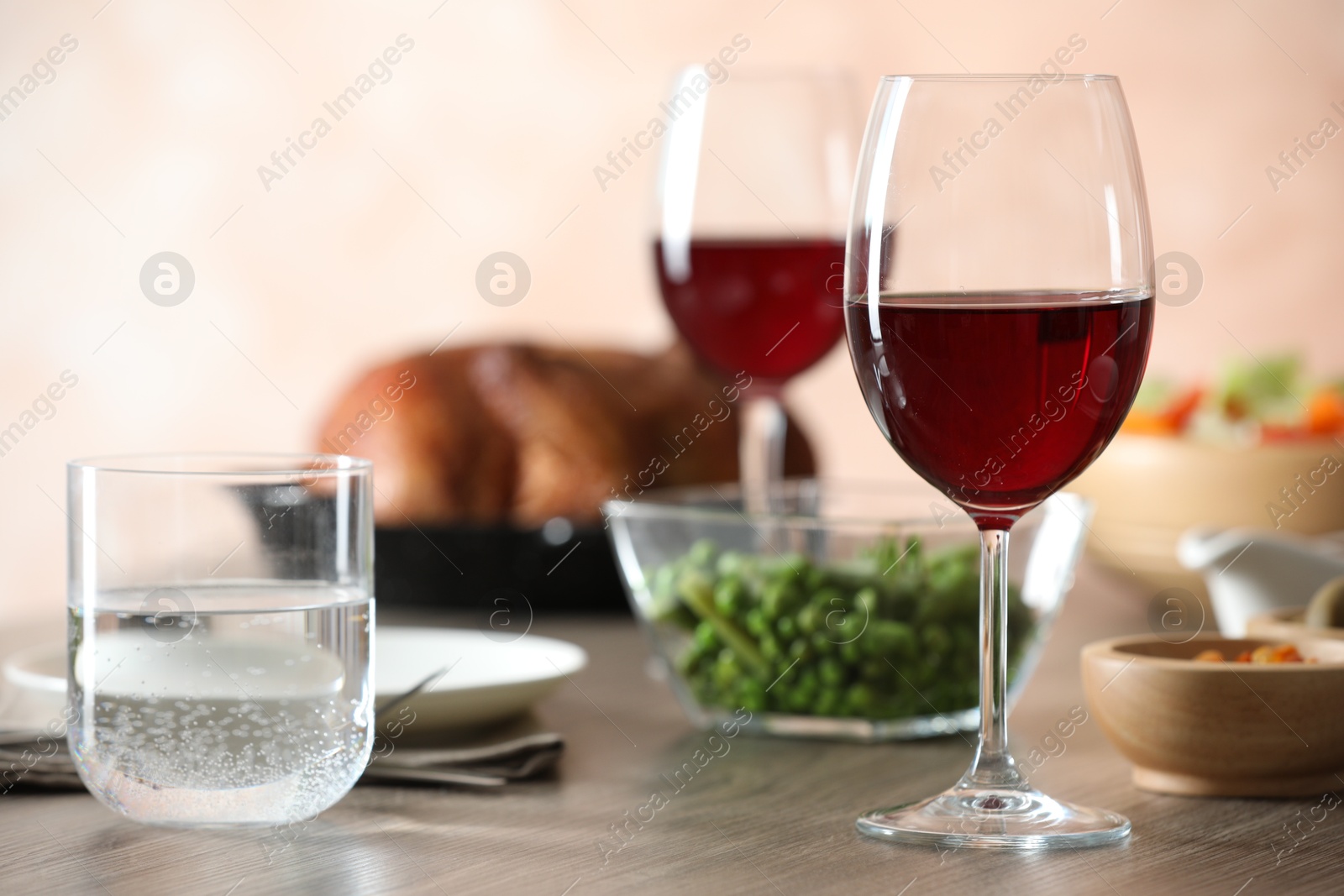 Photo of Red wine and delicious dinner served on wooden table, closeup