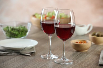 Photo of Red wine and delicious dinner served on wooden table