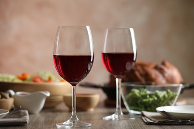 Photo of Red wine and delicious dinner served on wooden table, closeup