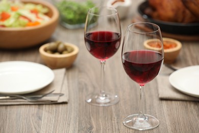 Photo of Red wine and delicious dinner served on wooden table, closeup. Space for text