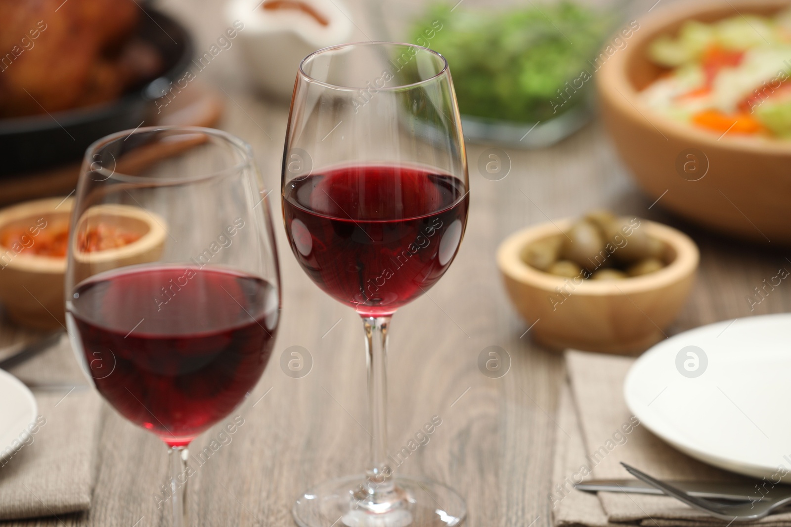 Photo of Red wine and delicious dinner served on wooden table, closeup. Space for text