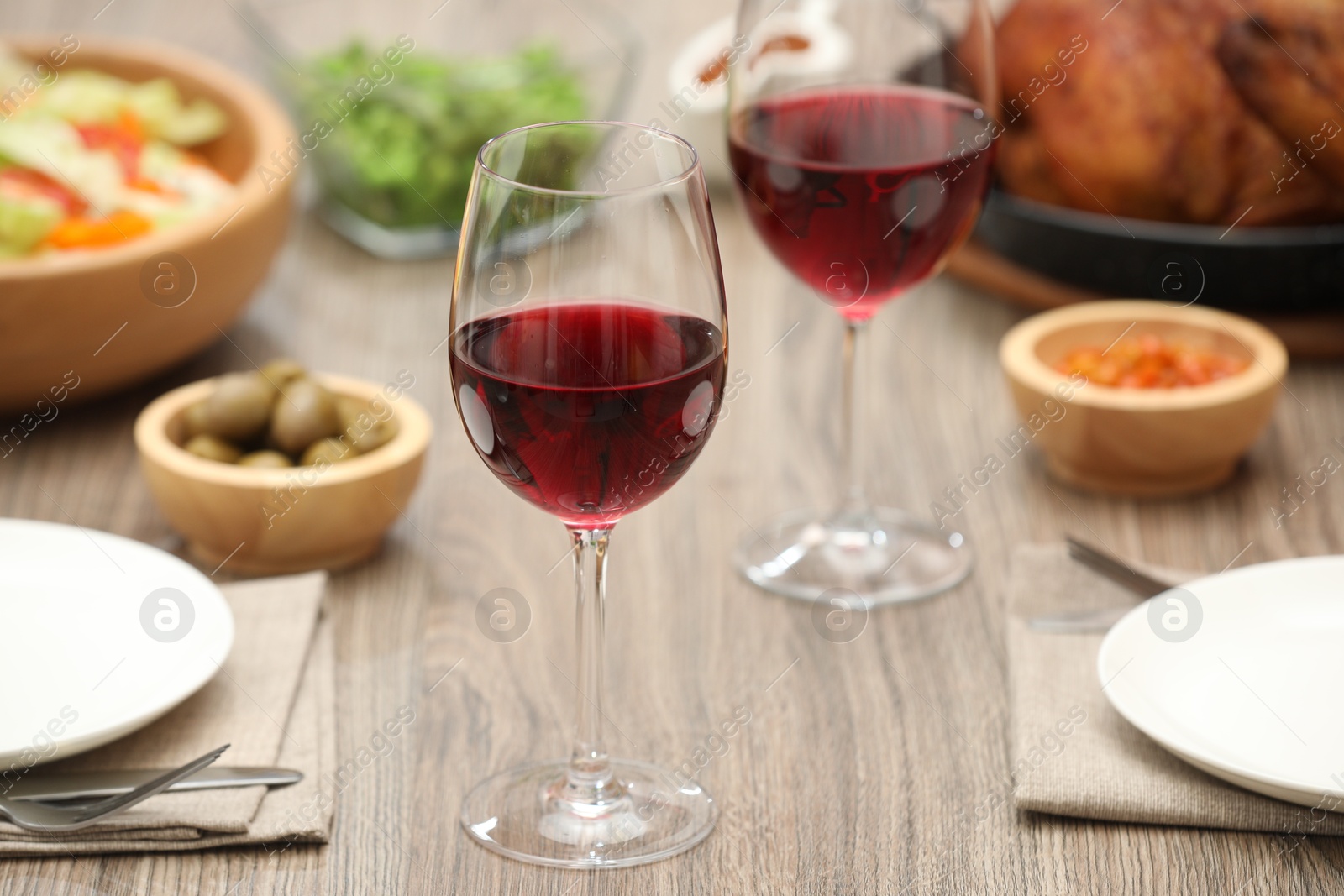 Photo of Red wine and delicious dinner served on wooden table