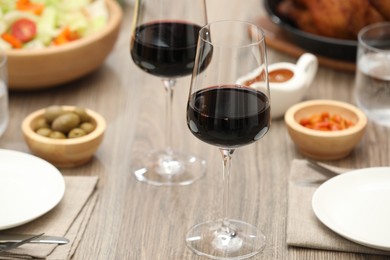 Photo of Red wine and delicious dinner served on wooden table, closeup. Space for text