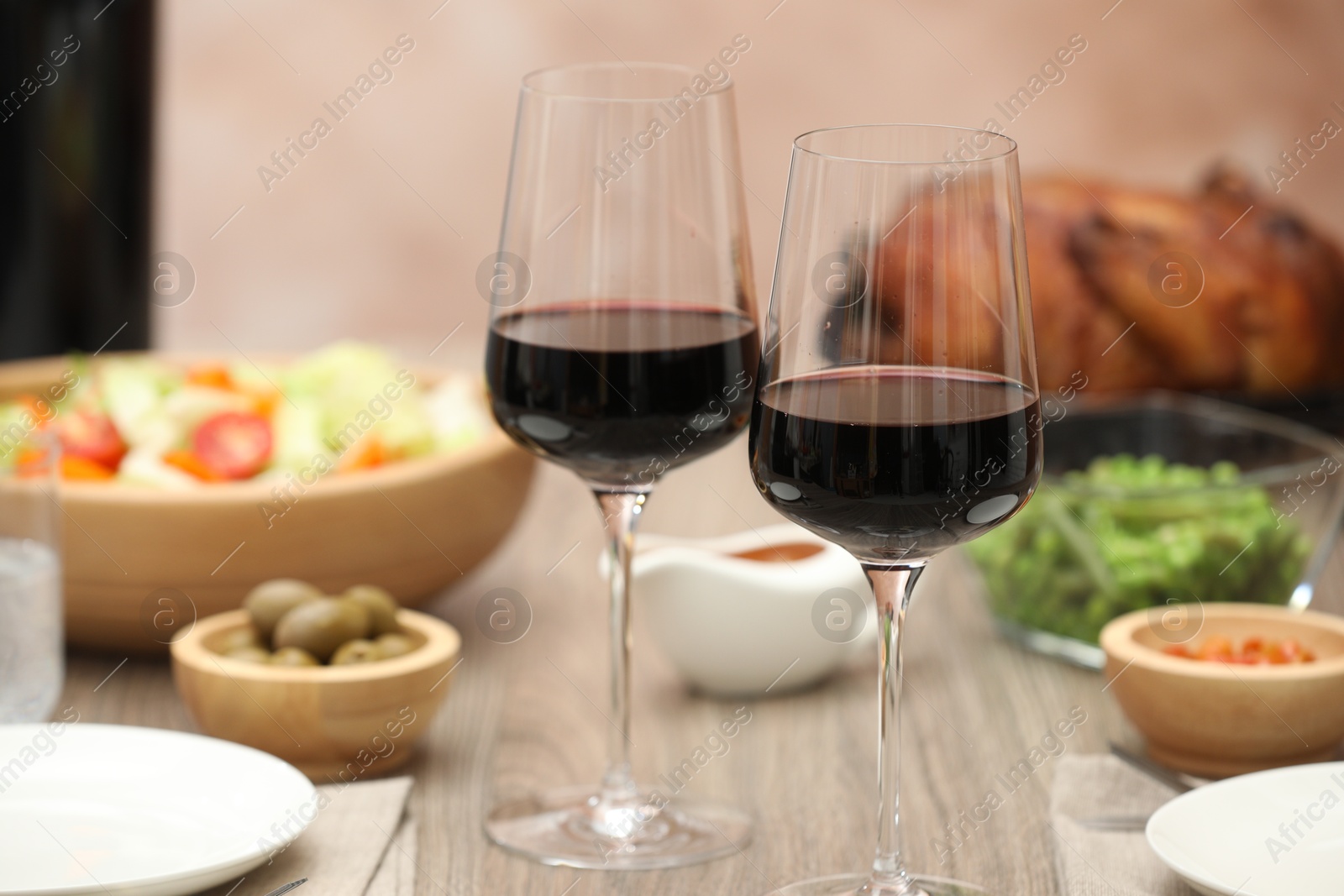 Photo of Red wine and delicious dinner served on wooden table, closeup