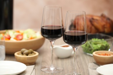 Photo of Red wine and delicious dinner served on wooden table, closeup