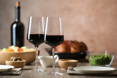 Photo of Red wine and delicious dinner served on wooden table, space for text