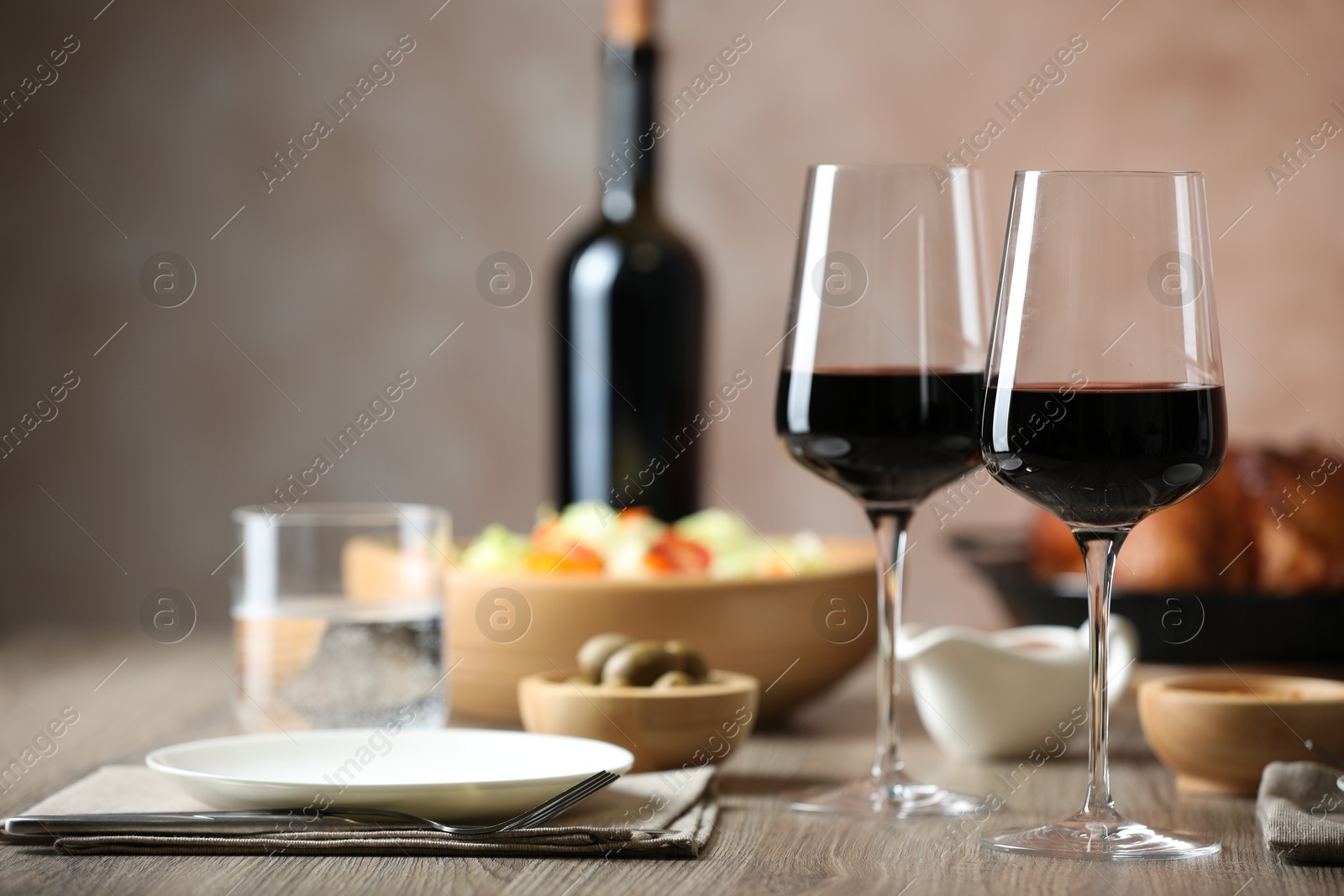 Photo of Red wine and delicious dinner served on wooden table, space for text