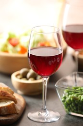 Photo of Red wine and delicious dinner served on grey table, closeup