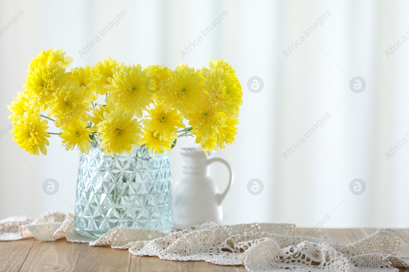 Photo of Beautiful yellow flowers in vase on wooden table at home. Space for text