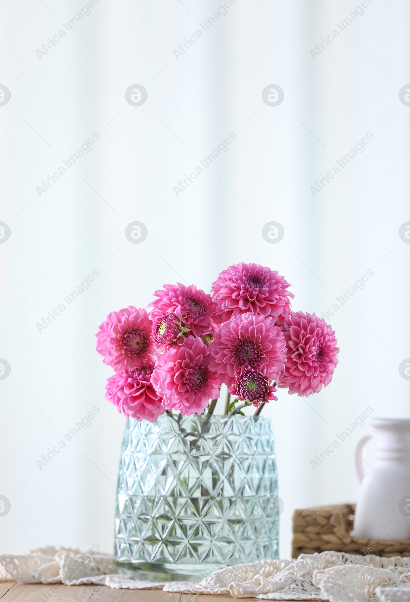 Photo of Beautiful pink flowers in vase on wooden table at home