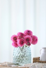 Photo of Beautiful pink flowers in vase on wooden table at home