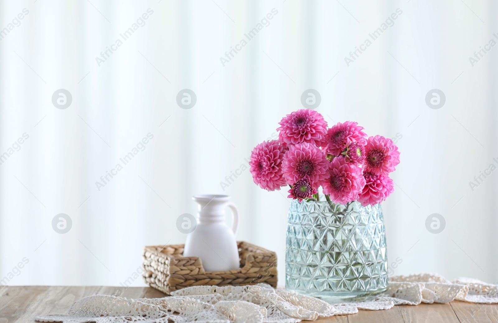 Photo of Beautiful pink flowers in vase on wooden table at home. Space for text