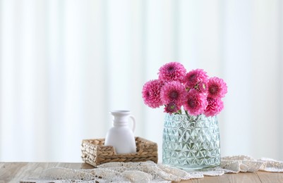 Photo of Beautiful pink flowers in vase on wooden table at home. Space for text