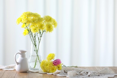 Photo of Beautiful yellow flowers in vase on wooden table at home. Space for text