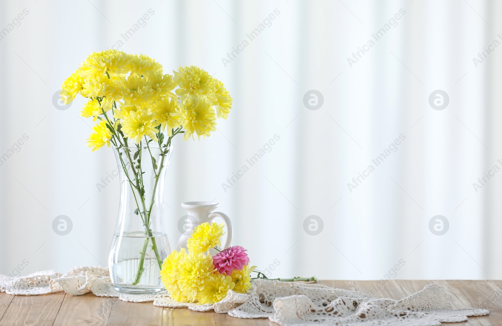 Photo of Beautiful yellow flowers in vase on wooden table at home. Space for text